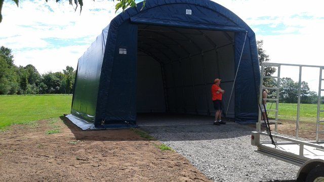 A man is standing in front of a large blue tent.