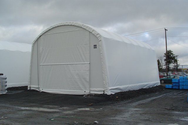 A large white tent is sitting in the middle of a parking lot.