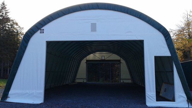 A large white and green tent is sitting on gravel