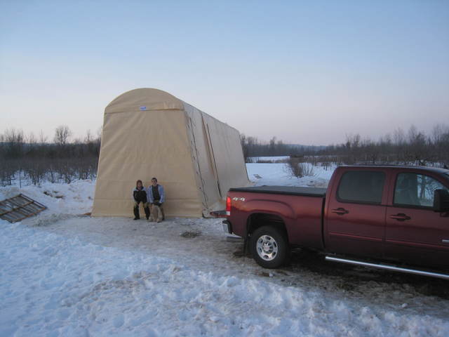 A red truck is parked next to a tent in the snow