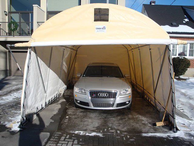 An audi car is parked under a tent in a driveway