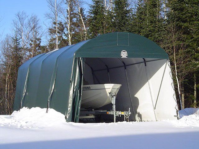 A boat is sitting inside of a tent in the snow