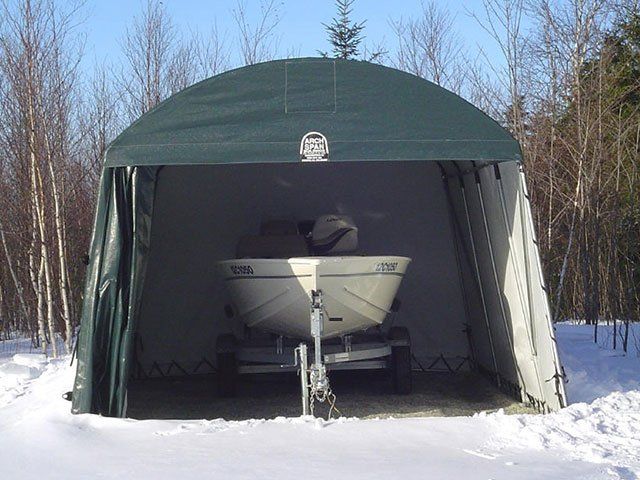 A boat is sitting inside of a tent in the snow