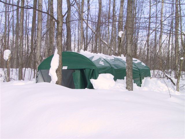 A green tent in the middle of a snowy forest