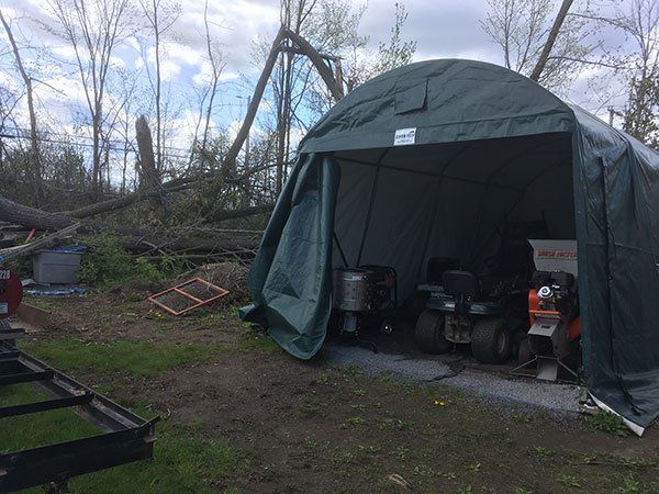 A green tent with a lawn mower inside of it