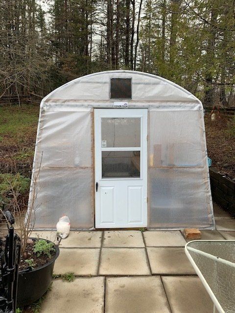 A greenhouse with a white door is sitting on a patio