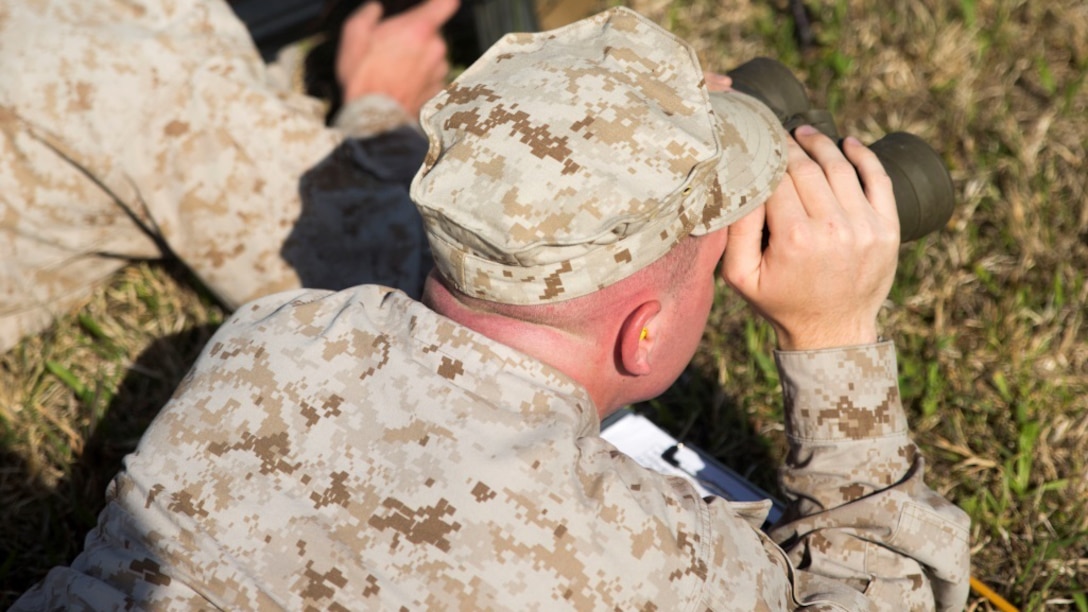 A Marine acts as a spotter during a Designated Marksman Course with the Division Combat Skills Center, April 6-17, 2015, aboard Camp Lejeune, N.C. The Marines worked in teams of two: a designated marksman and a spotter to help call the shot.