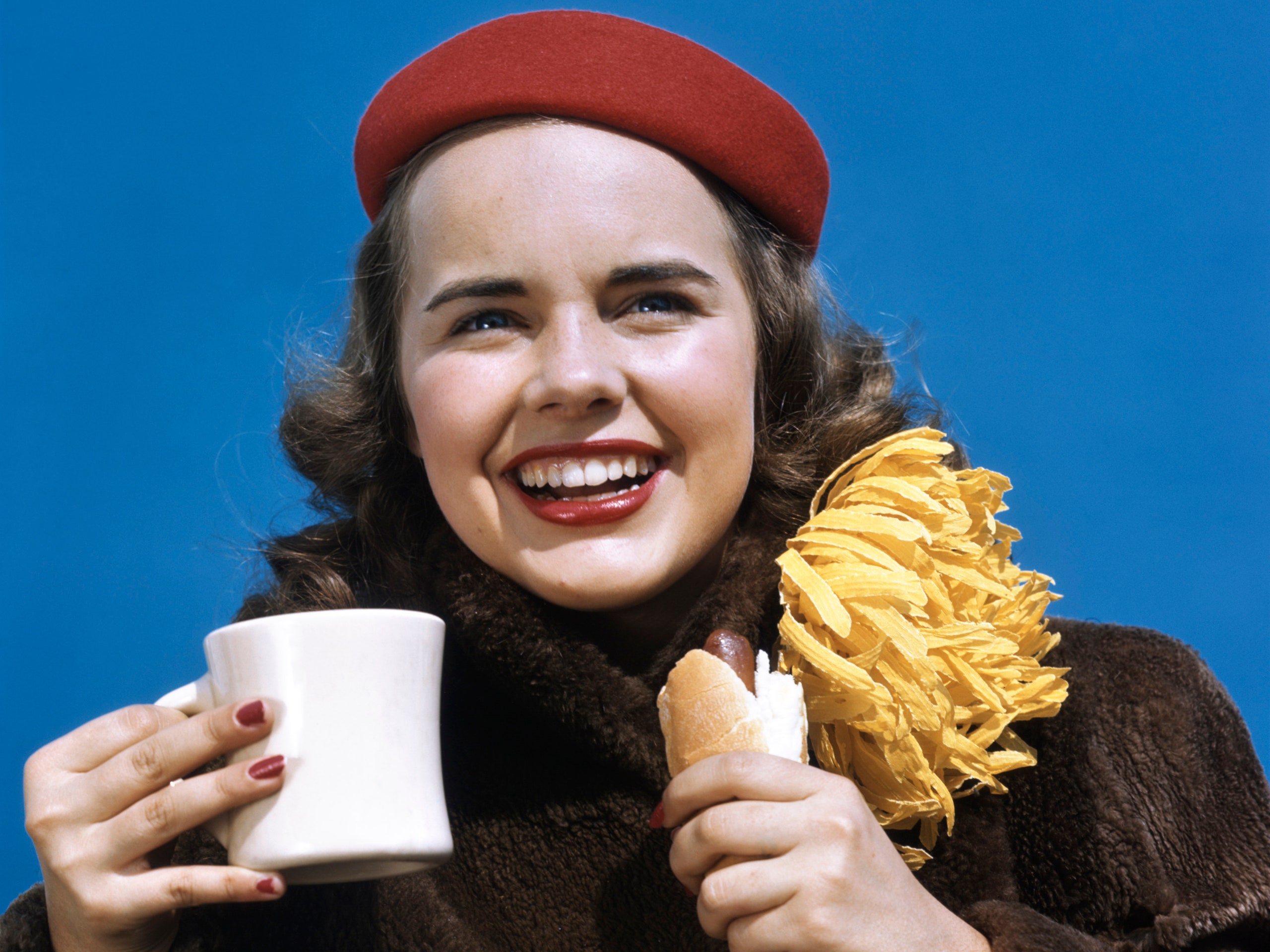 Vintage image of young woman holding coffee and hotdog