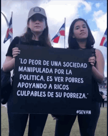 two women holding a black sign that says " lo peor de una sociedad manipulada por la politica