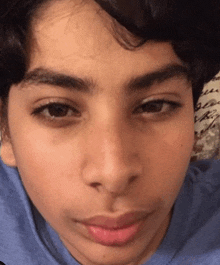 a close up of a young man 's face with a blue shirt