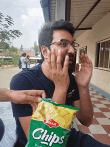 a man is holding a bag of bikaji chips in front of his face