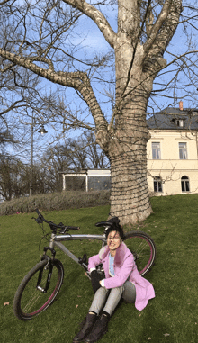 a woman in a pink coat sits next to a bike