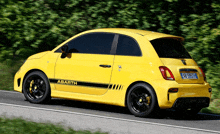 a yellow abarth is driving down a road