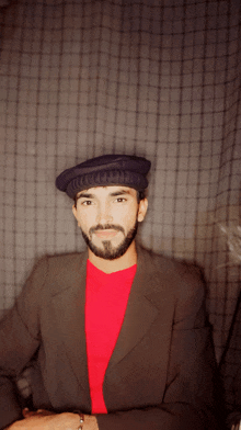 a man with a beard is wearing a hat and a red shirt