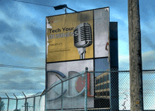 a billboard with a microphone and the words tech your business on it