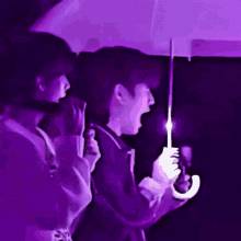 a man and a woman are holding umbrellas in a dark room with purple lights .