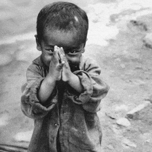 a black and white photo of a child praying with his hands folded