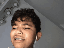 a boy with braces on his teeth is wearing ear buds