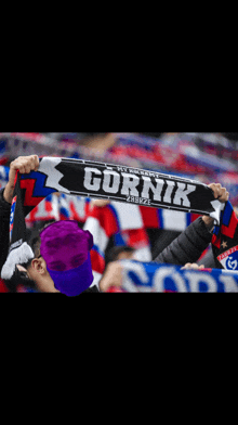 a person holding up a scarf that says gornik on it