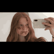 a girl with red hair is taking a picture of herself with red kisses on her face