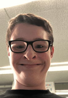 a young man wearing glasses makes a funny face in front of a sign that says sweat