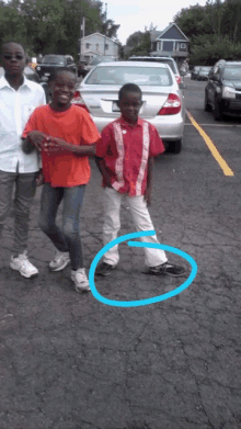 three young boys are standing in a parking lot with a blue circle around their shoes