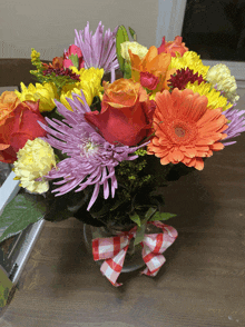 a vase filled with colorful flowers has a red and white checkered bow