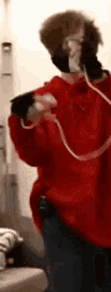 a person wearing a red sweater and headphones is standing in front of a wall .