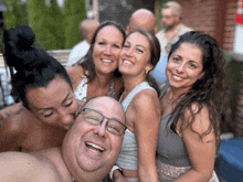 a group of people posing for a picture including a shirtless man wearing glasses