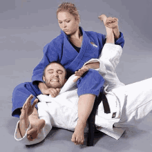 a woman is wrestling a man in a blue kimono .