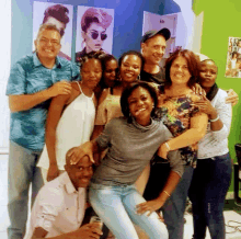 a group of people posing for a picture in front of a wall with pictures on it