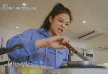 a woman is holding a knife over a pan while cooking .