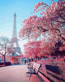 the eiffel tower is surrounded by pink flowers and a bench in the foreground