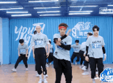 a group of young men are dancing in a room with a blue wall behind them .