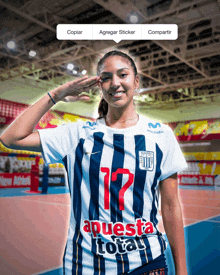 a woman wearing a jersey with the number 12 on it salutes