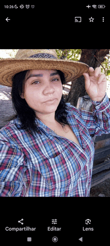 a woman wearing a plaid shirt and a straw hat is on a phone screen