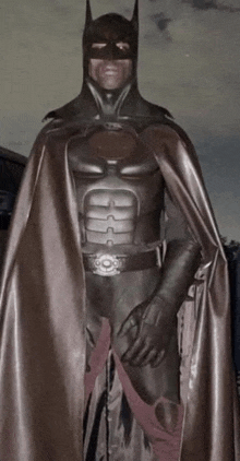 a man in a batman costume with a cape and gloves