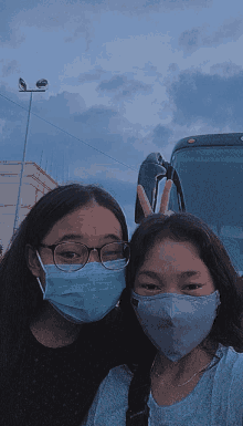 two girls wearing face masks pose for a photo