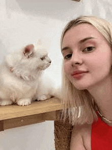 a woman is sitting next to a white kitten on a wooden table .