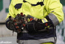 a man in a yellow jacket is holding a bunch of canisters