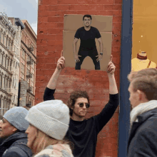 a man holds up a cardboard sign with a picture of tom cruise on it