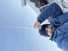 a man wearing a blue jacket and a black beanie is holding a long icicle