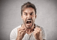 a man with a beard is making a very angry face with his mouth open .