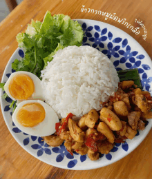 a plate of food with rice chicken and eggs on a wooden table