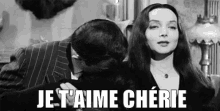 a man is kissing a woman on the cheek in a black and white photo with the words `` je t'aime cherie '' .