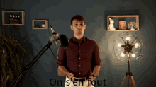 a man in a red shirt stands in front of a microphone with the words " on s'en fout " below him