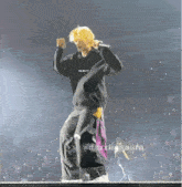 a man in a black hoodie is dancing on a stage with a microphone .