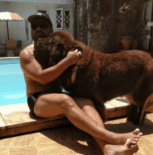 a shirtless man is sitting next to a brown dog