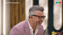 a man wearing glasses and a pink suit is laughing in a masterchef argentina video