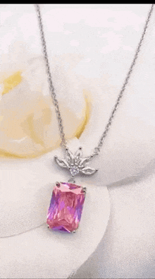 a close up of a necklace with a pink and purple stone on a flower .